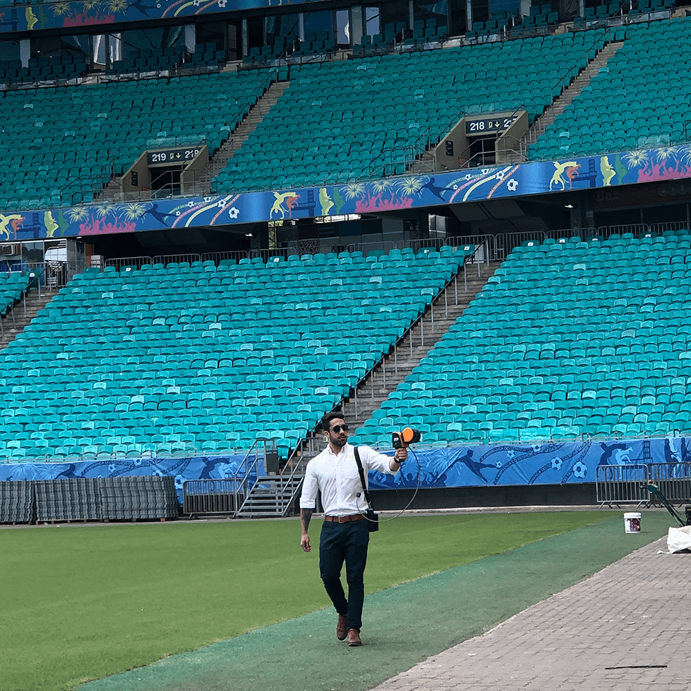 Smartly dressed man walking through a stadium with a mobile LiDAR scanner